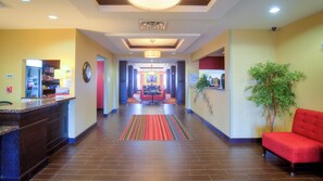 A hotel lobby with a reception desk, a dining area, and a red sofa.