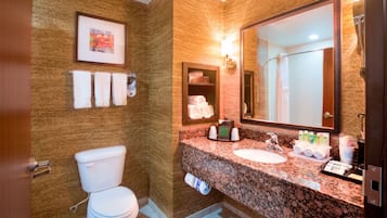Een badkamer met toilet, wastafel en grote spiegel. Handdoeken en toiletartikelen liggen op het aanrecht.