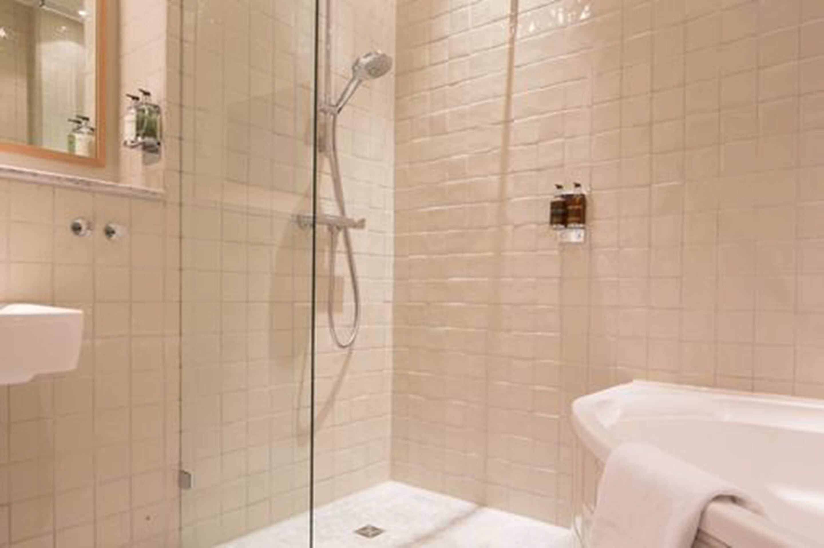 A modern bathroom with a glass shower enclosure, a white bathtub, and a visible toilet.