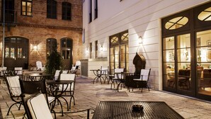 An outdoor patio area with tables and chairs, a potted plant, and a brick building in the background. - monbijou Hotel Berlin (Berlin)