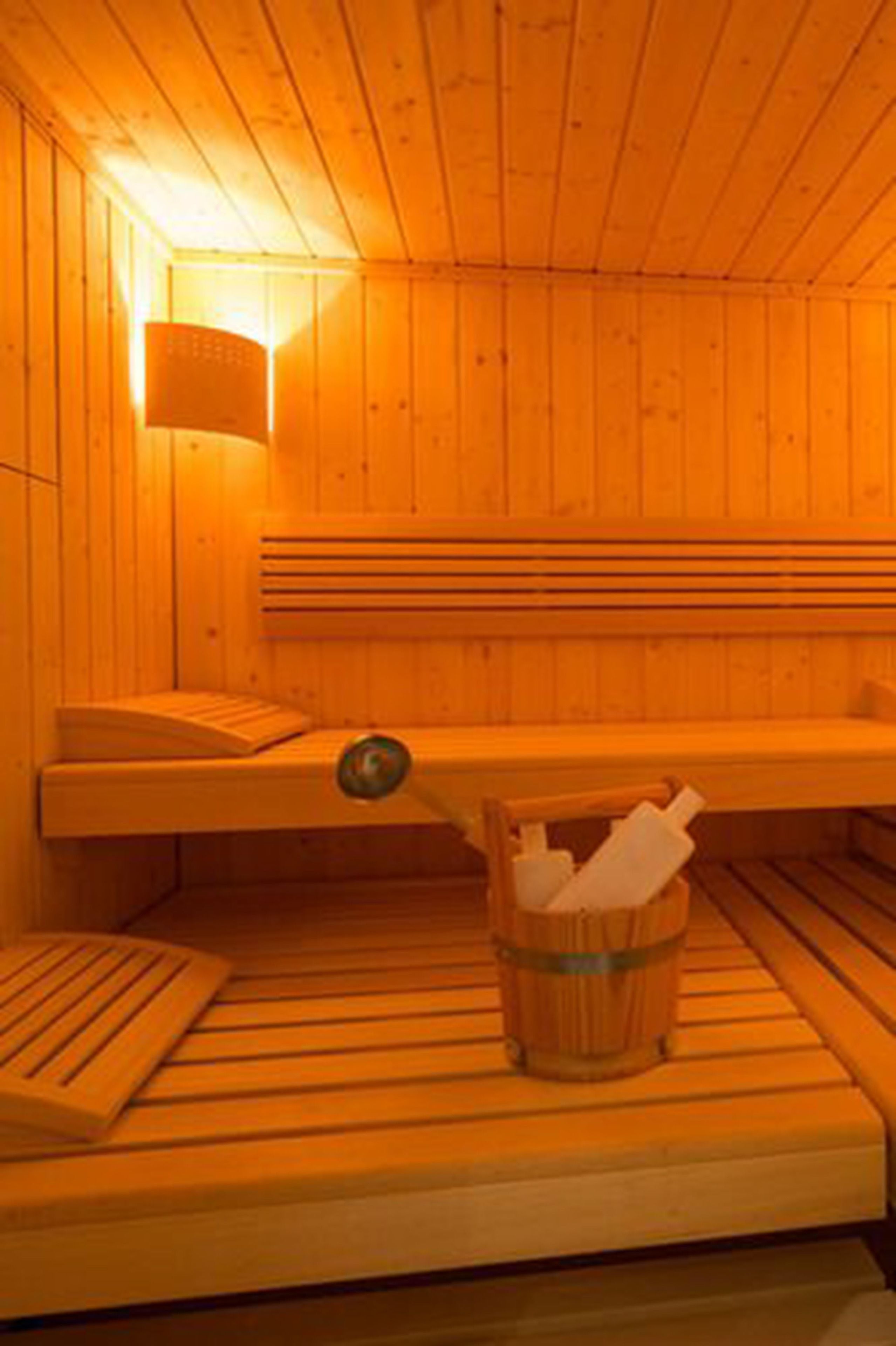 A sauna with wooden benches and a bucket for towels.