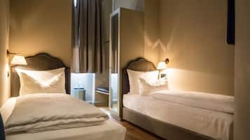 A hotel room with two single beds, a nightstand, and a mirror.