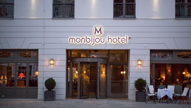 The exterior of the Monbijou Hotel with a revolving door entrance, outdoor seating area, and illuminated signage. - monbijou Hotel Berlin (Berlin)