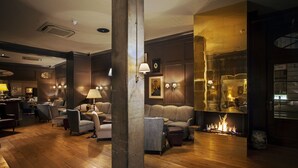 A cozy lounge area with a fireplace, comfortable seating, and a bar area in the background. - monbijou Hotel Berlin (Berlin)