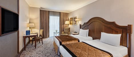 A hotel room with two beds, a desk, a chair, a TV, and a window with curtains.