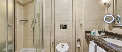 Un baño moderno con ducha de vidrio, inodoro con un diseño floral, tocador con espejo y una planta en maceta.