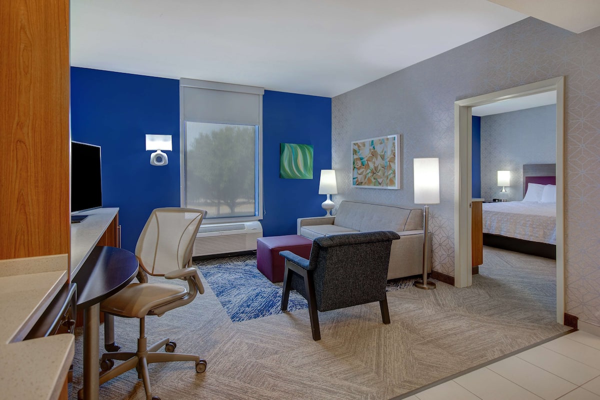 Una habitación de hotel con escritorio, silla, sofá y cama.
