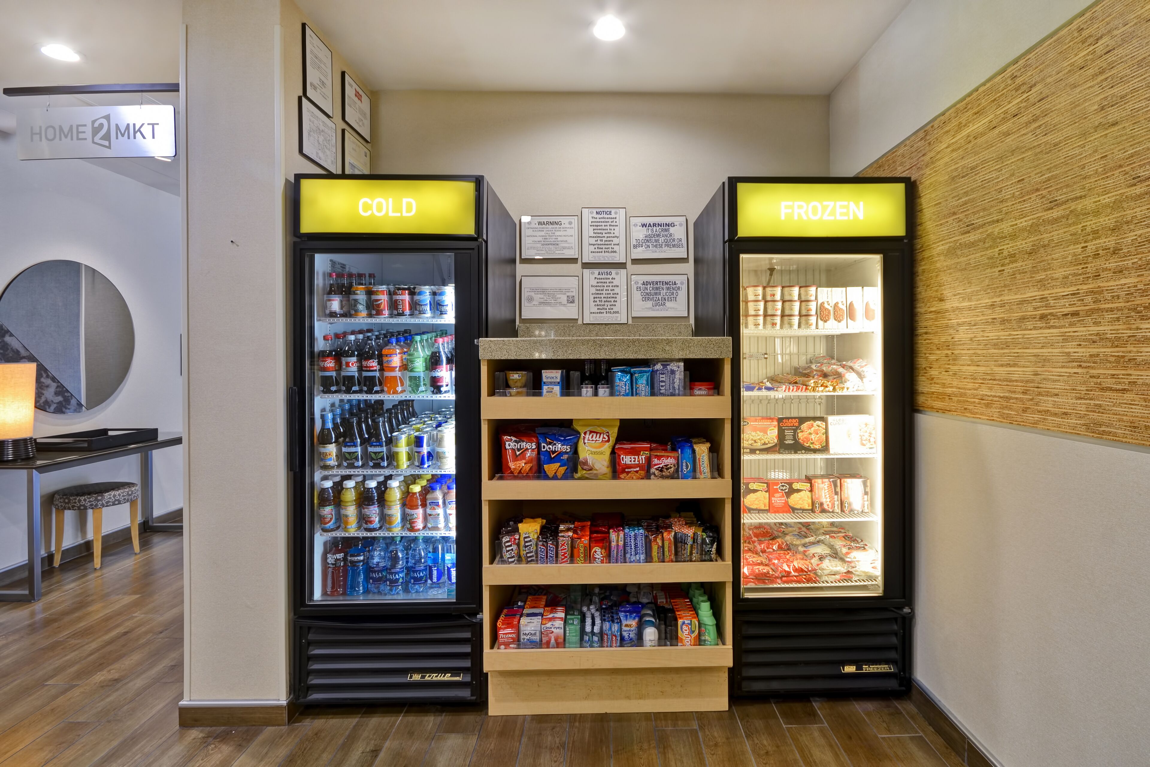 A section of a store with two refrigerated display cases labeled "COLD" and "FROZEN," stocked with beverages and snacks.