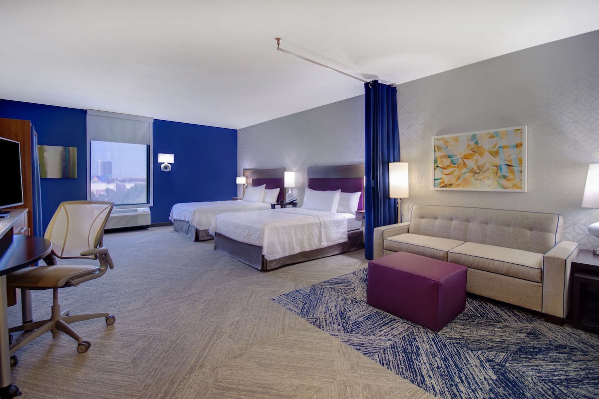 Una habitación de hotel con dos camas, un sofá, un escritorio y una silla.