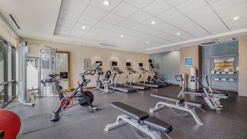 Un gimnasio con cintas de correr, elípticas y máquinas de pesas.