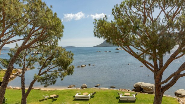 A serene lakeside setting with outdoor seating areas and large trees providing shade. - Casa Santini x Roc Seven (Porto-Vecchio)