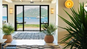 A hotel lobby with a large woven light fixture, a patterned rug, and potted plants. - Casa Santini x Roc Seven (Porto-Vecchio)