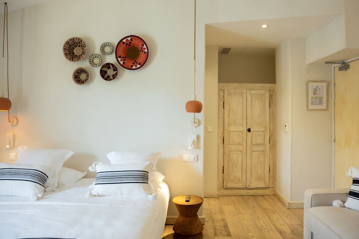 A hotel room with a bed, bedside tables, a wooden wardrobe, and wall decorations.
