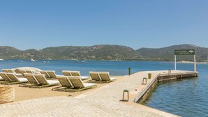 A beachside view with lounge chairs and a sign indicating 'Casa Santini x Roc Seven'. - Casa Santini x Roc Seven (Porto-Vecchio)