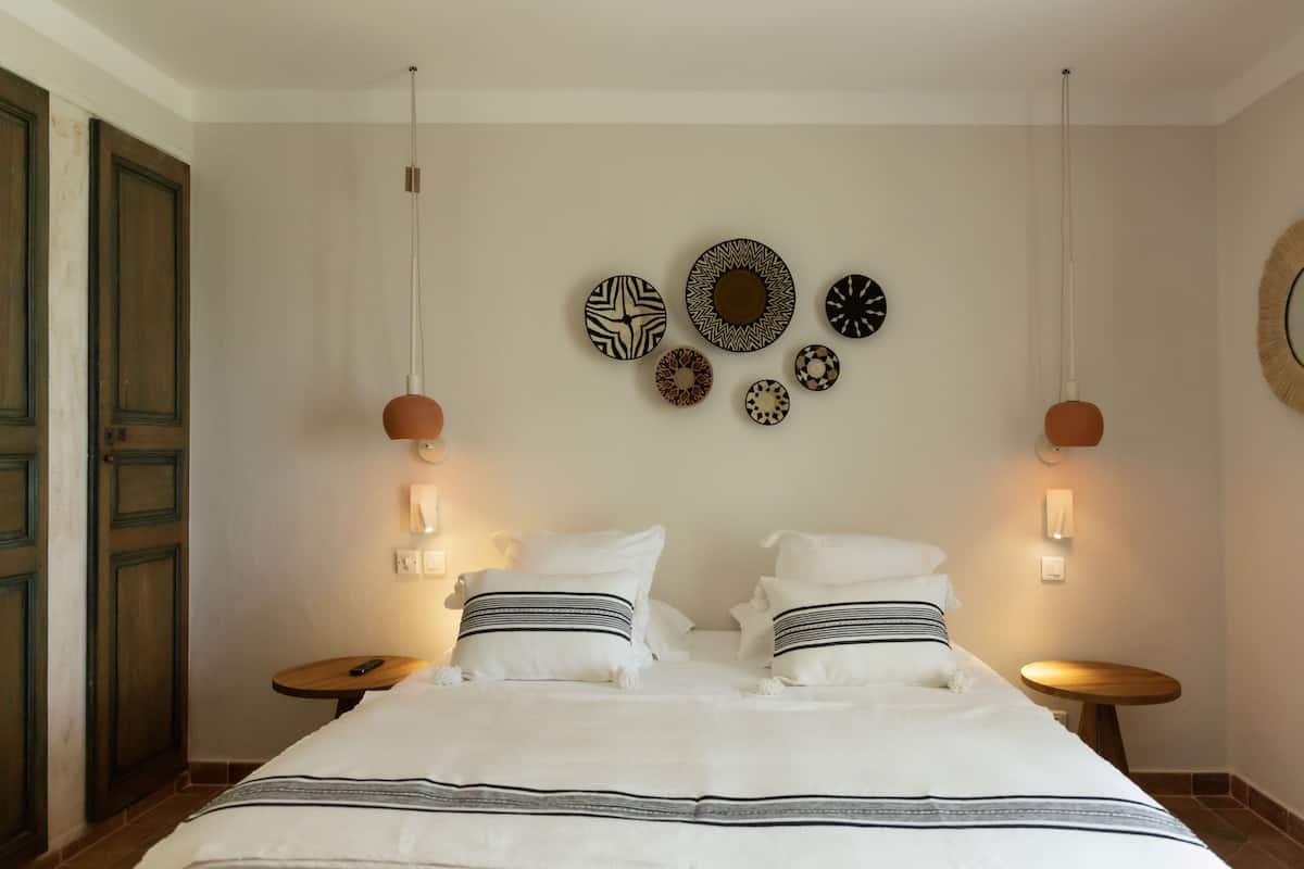A neatly arranged bedroom with a large bed, two bedside tables, and wall-mounted decor.