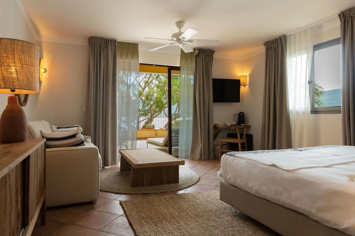 A hotel room with a bed, a desk, a chair, a sofa, a coffee table, and a TV.