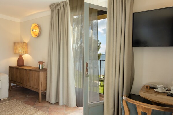A room with a wooden console table, a lamp, a TV, and a view of the outdoors through a glass door.