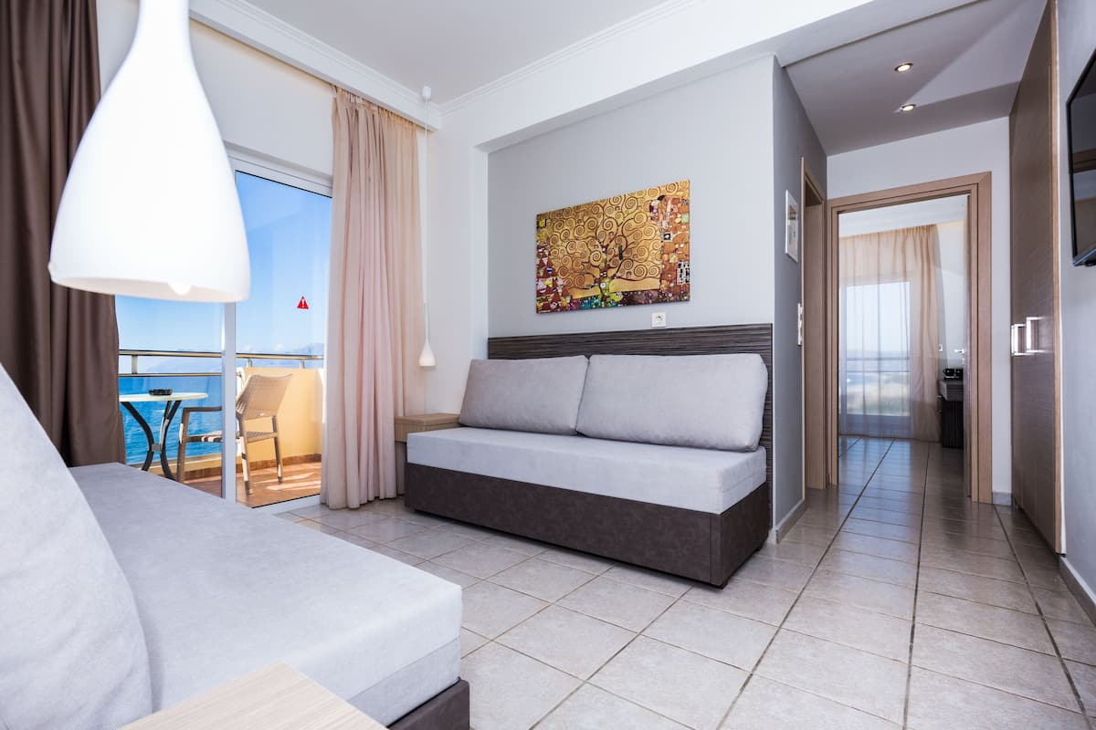 Une chambre d’hôtel moderne dotée d’un canapé, d’une table à manger et d’un balcon offrant une vue sur la mer.