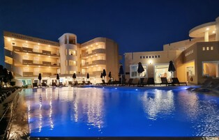 Una piscina al aire libre, sombrillas, sillones reclinables de piscina