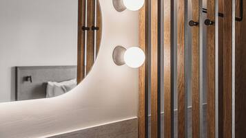 A bathroom with a large mirror, two round lights, a faucet, and wooden slats.