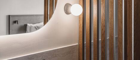 Un baño con un espejo grande, dos luces redondas, un grifo y listones de madera.