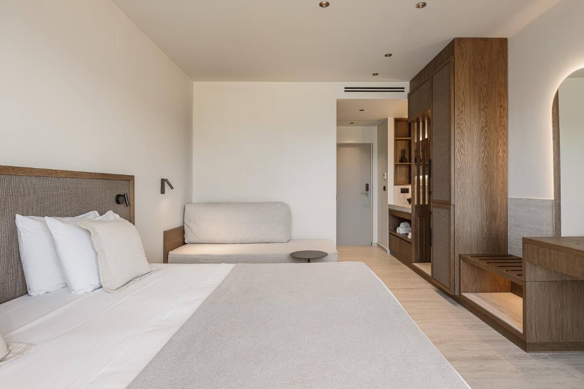 Une chambre d’hôtel moderne dotée d’un grand lit, d’un coin salon et d’une armoire en bois.