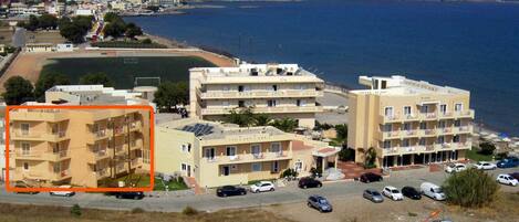 Un hotel frente al mar con varios pisos, balcones y un estacionamiento.