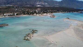 Vista aérea de una zona costera con aguas turquesas cristalinas, playas de arena y afloramientos rocosos.