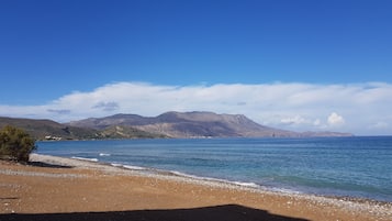 En strand med krystalklart hav og fjerne bjerge.