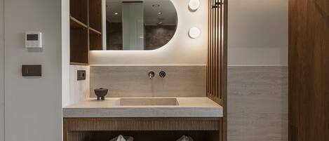 A modern bathroom with a large mirror, a sink, and a towel rack.