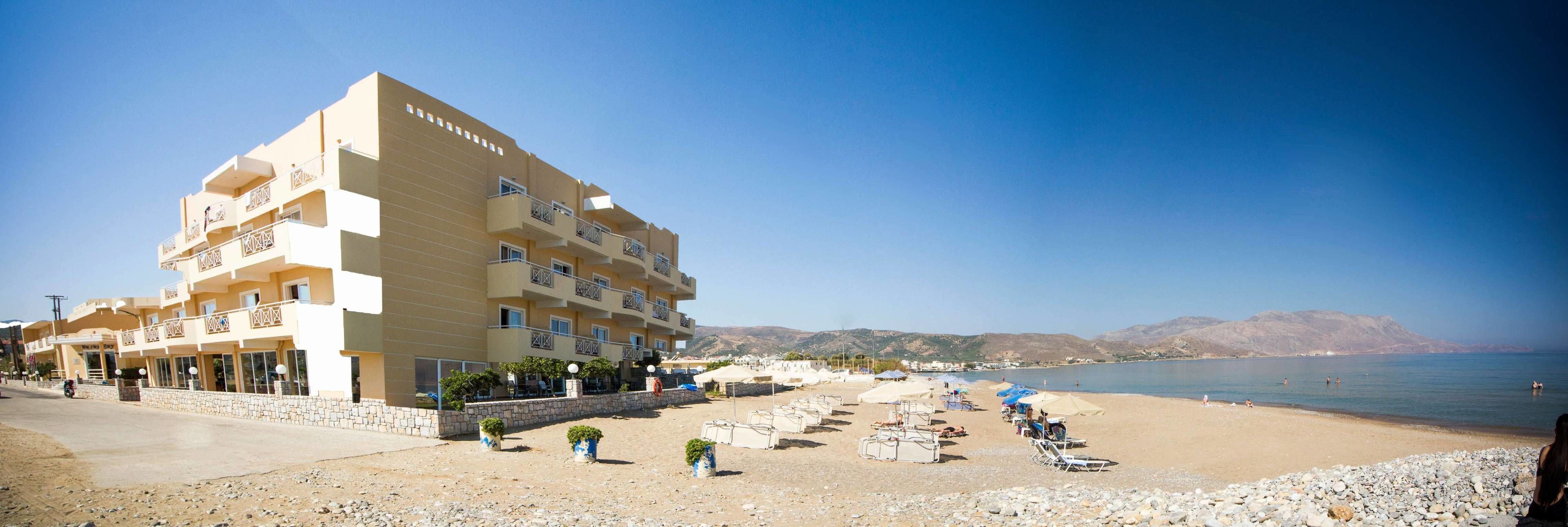 A multi-story hotel with balconies, a beachside location, and a view of the sea.