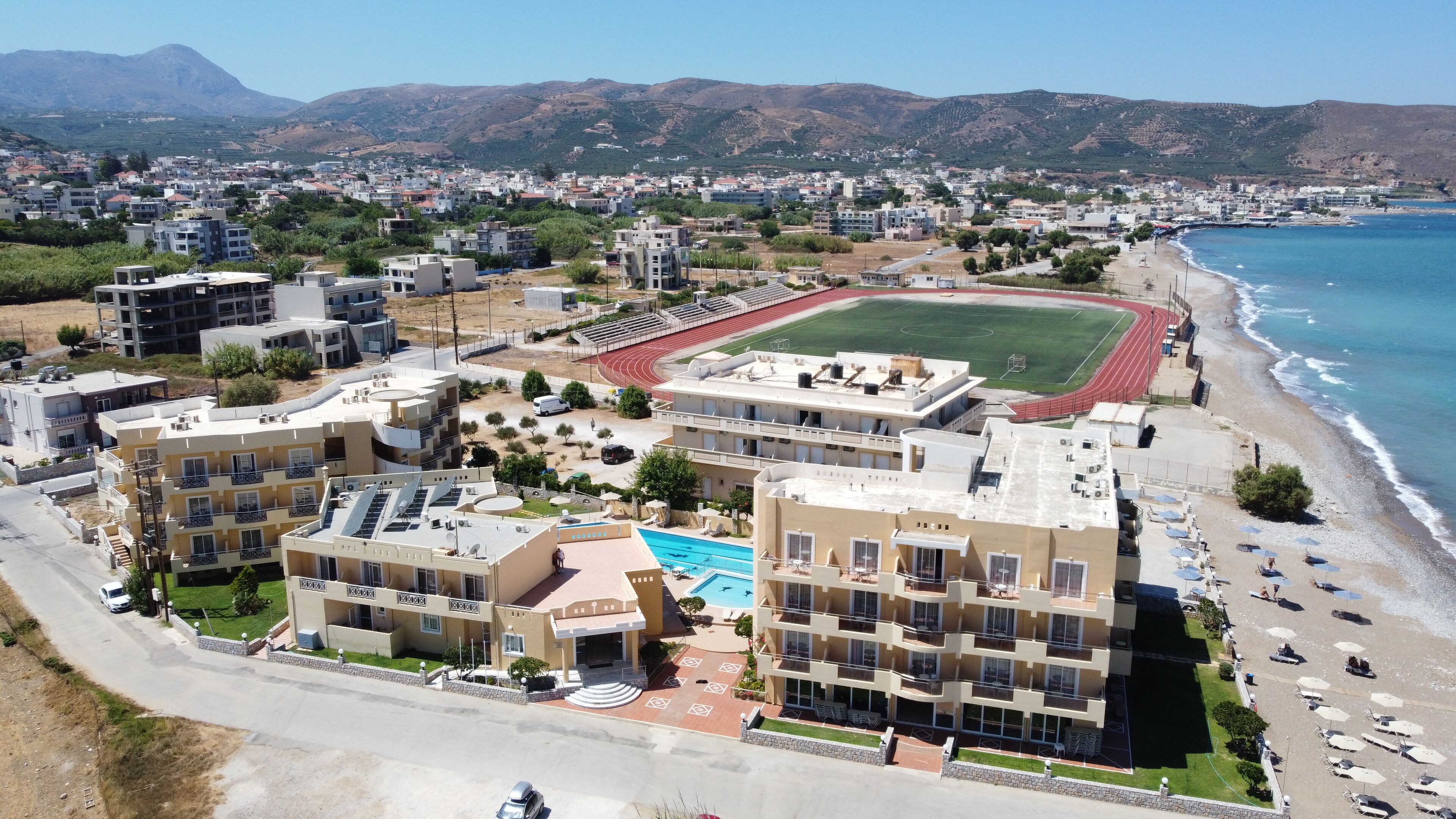A coastal hotel with multiple buildings, a swimming pool, and a beach area.