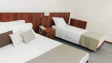 Una habitación de hotel con dos camas, una mesita de noche con lámpara y teléfono.