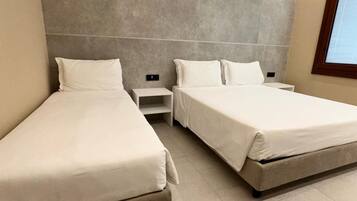 A modern hotel room with two single beds, a small bedside table, and a large window.