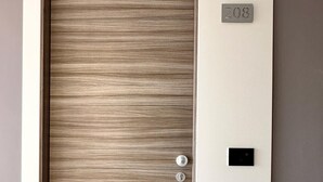 A door with a textured panel, a numeric keypad lock, and a small control panel on the wall. - Hotel Al Giardino (Treviso)