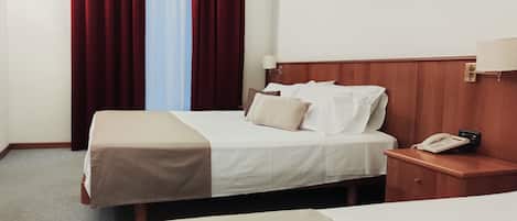 A hotel room with a bed, a bedside table with a phone, and a painting on the wall.