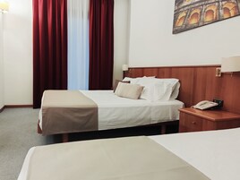 Una habitación de hotel con una cama, una mesita de noche con teléfono y un cuadro en la pared.