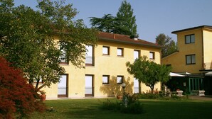 A yellow building with multiple windows and balconies, surrounded by greenery and trees. - Hotel Al Giardino (Treviso)