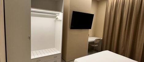A hotel room with a bed, a desk, a TV, a wardrobe, and a bathroom.