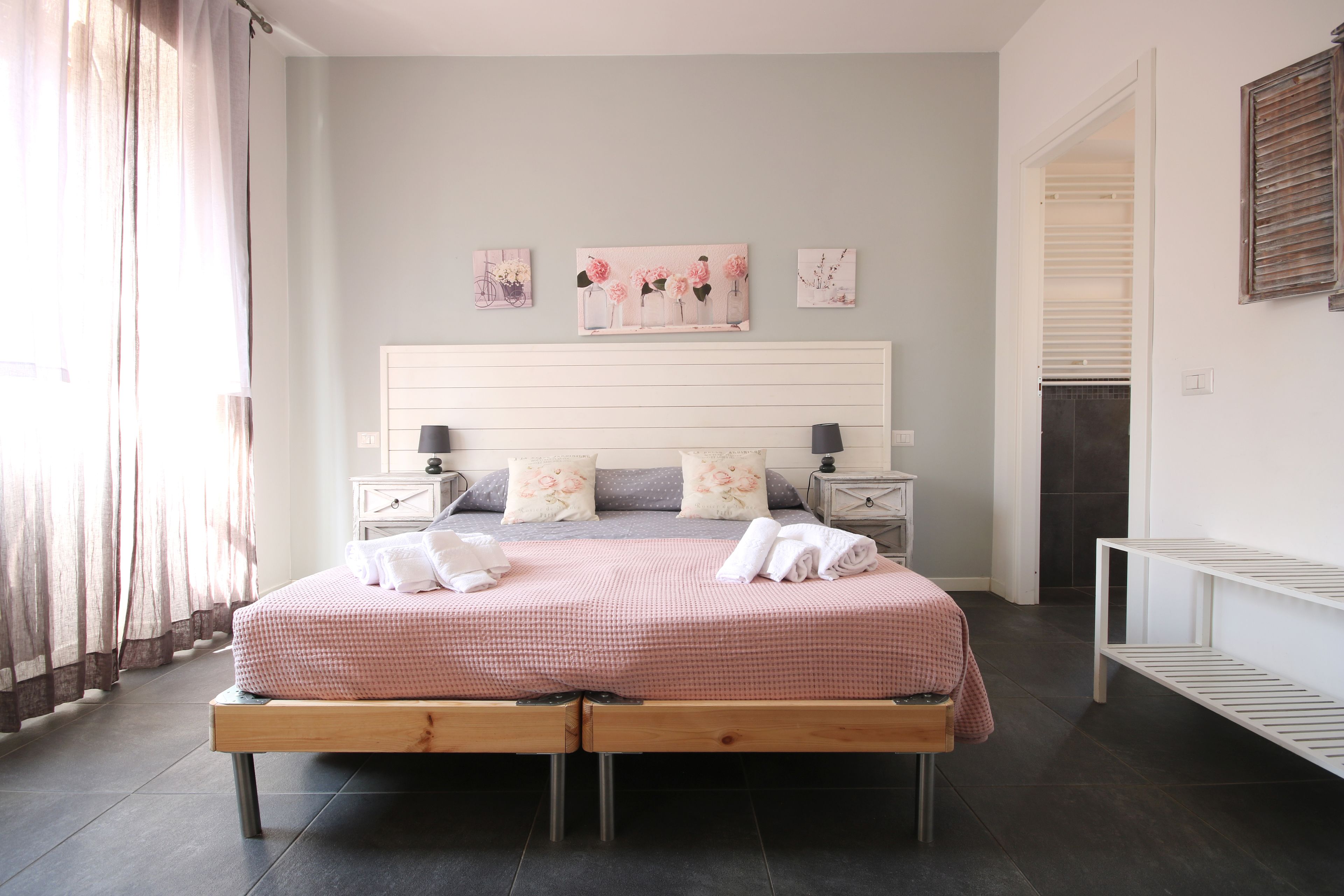 Une chambre à coucher bien rangée, avec un lit, des tables de chevet et des œuvres d’art accrochées au mur.