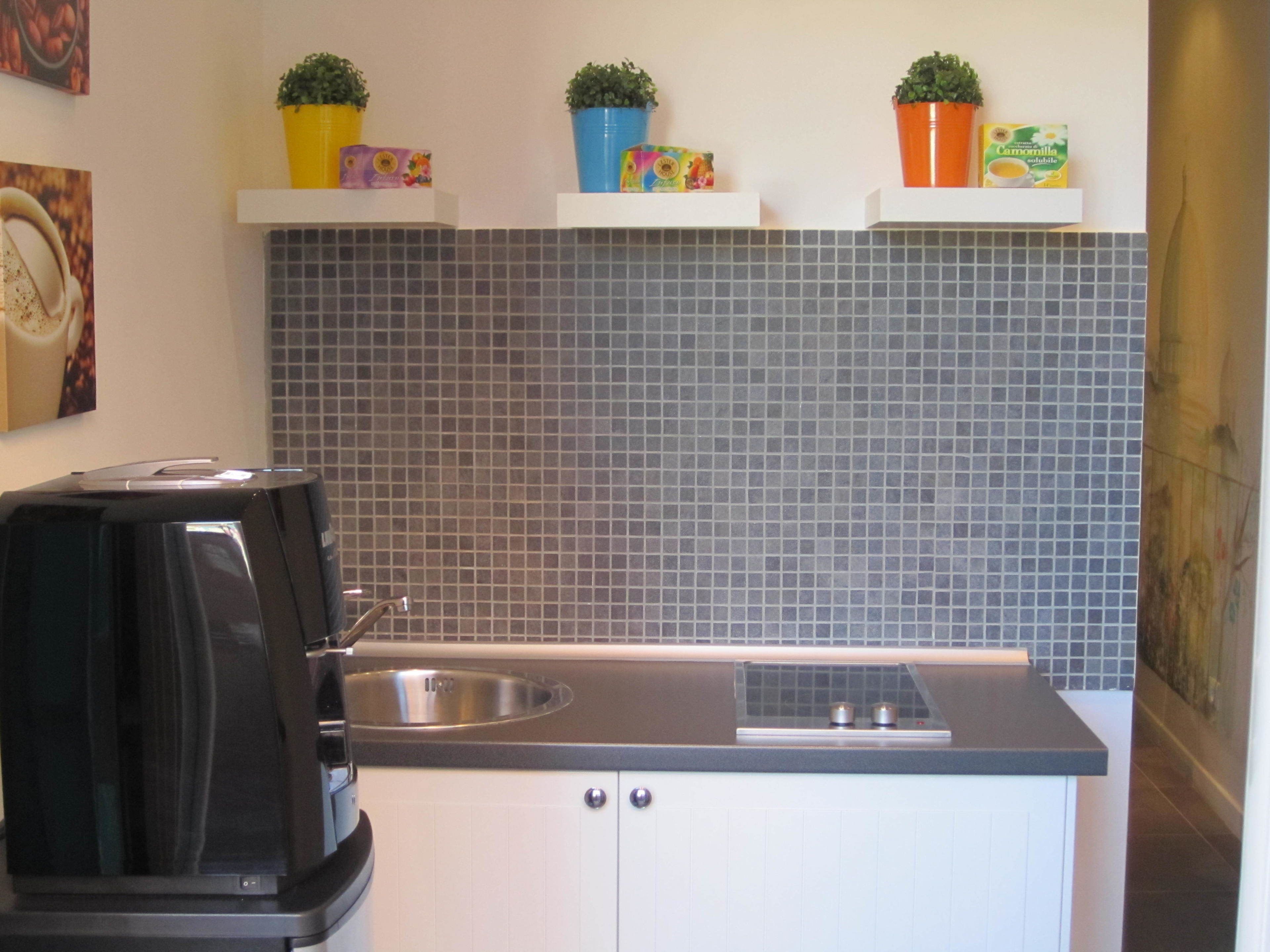 A kitchen with a coffee maker, a sink, and a tiled backsplash.