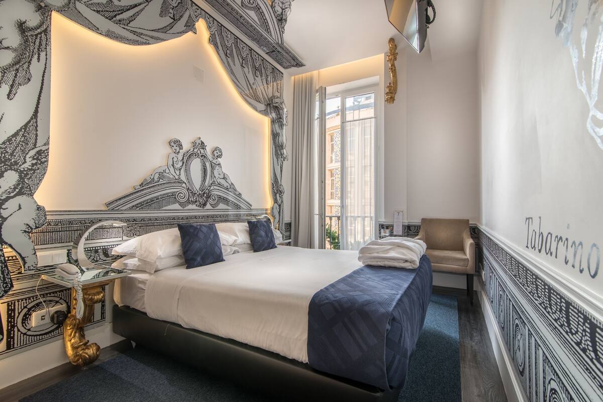 Ein Hotelzimmer mit einem großen Bett, einem Nachttisch mit Telefon und einem Sessel.