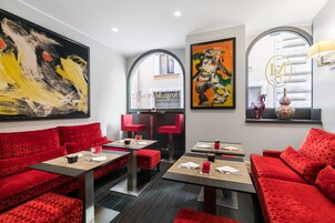 Un ristorante moderno con sedute imbottite rosse, opere d'arte astratte alle pareti e un logo ben visibile.