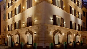 A multi-story hotel with a classic architectural design, featuring arched windows and a balcony with a black railing. - Hotel Mancino 12 (Rome)