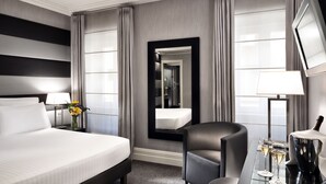 A hotel room with a large bed, a desk with two glasses of champagne, a chair, and a mirror. - Hotel Mancino 12 (Rome)