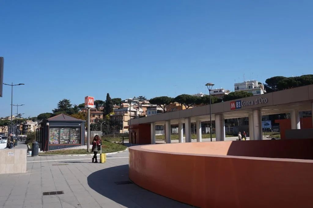 Une place publique avec un bâtiment moderne, un kiosque et un ciel dégagé.