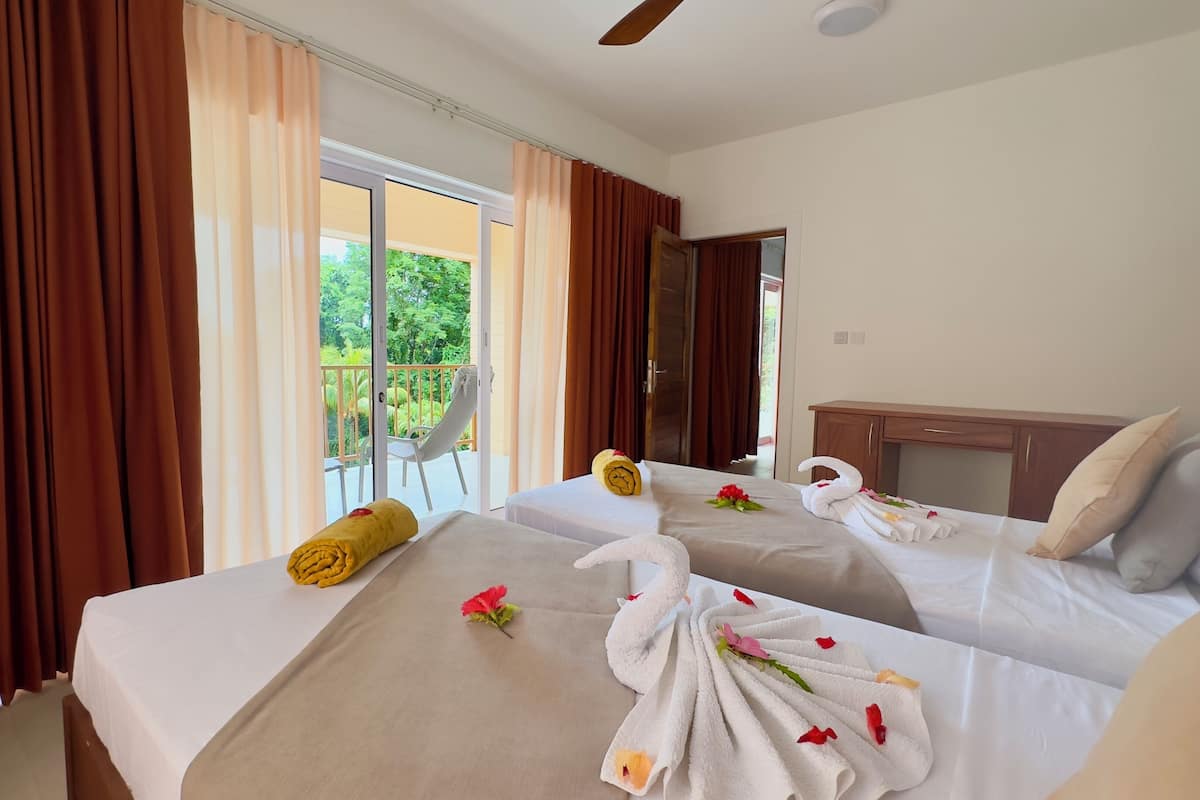 Quarto de hotel com duas camas, cada uma decorada com toalhas e flores.