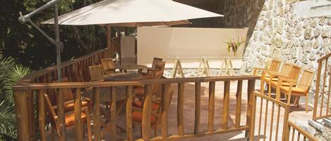 An outdoor patio with wooden furniture and a large umbrella.