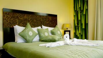 A neatly made bed with green bedding and white pillows, a decorative headboard, and a green curtain.