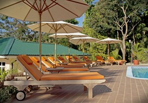 Un espace aménagé au bord de la piscine, avec des chaises longues et des parasols.